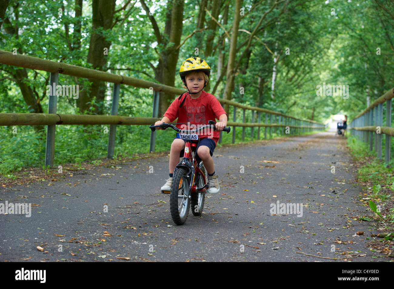 Child blond boy 4 years old riding bicycle with safety helmet in park