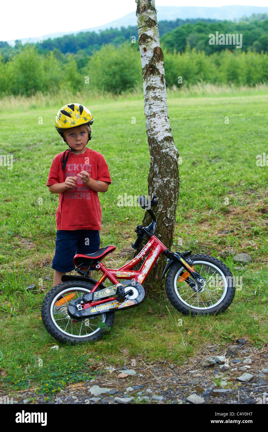 Child blond boy 4 years old riding bicycle with safety helmet in park