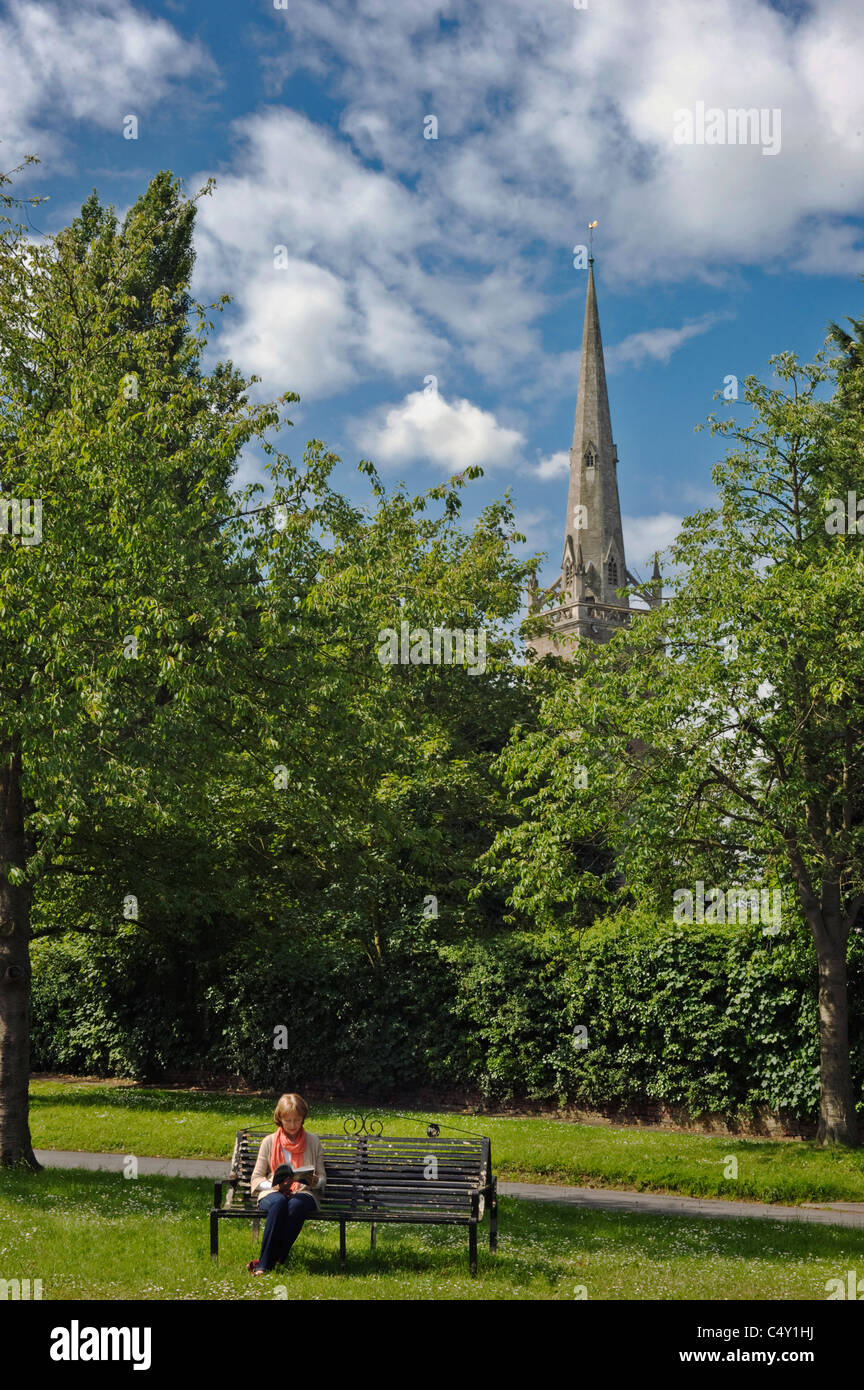 Woman reading seated on a bench on an English village green Stock Photo ...