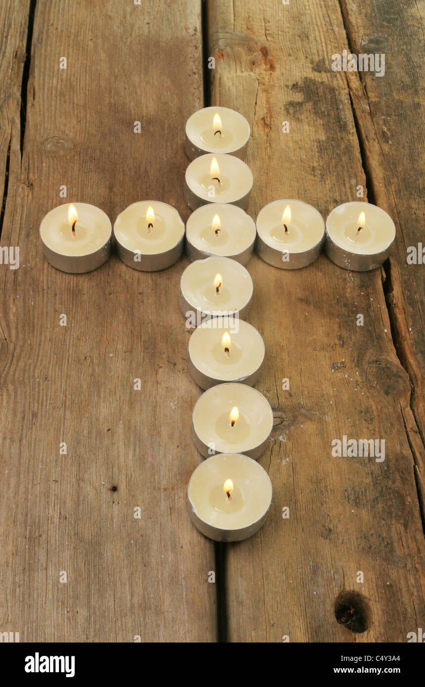 Candles form the shape of a cross on old rustic wood Stock Photo