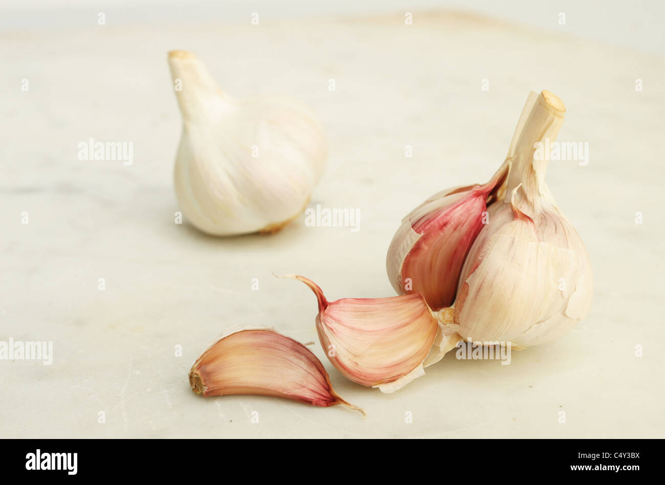 Garlic bulbs and cloves on a marble worktop with differential focus Stock Photo