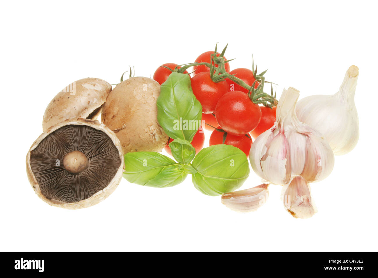 Complimentary food ingredients of mushrooms,basil,tomatoes and garlic isolated on white Stock Photo