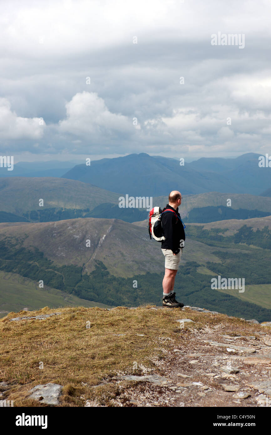 Walker on the summit plateau of Ben Oss with Meall Odhar (656m) behind and Beinn Dorain (1076m) in the distance Stock Photo