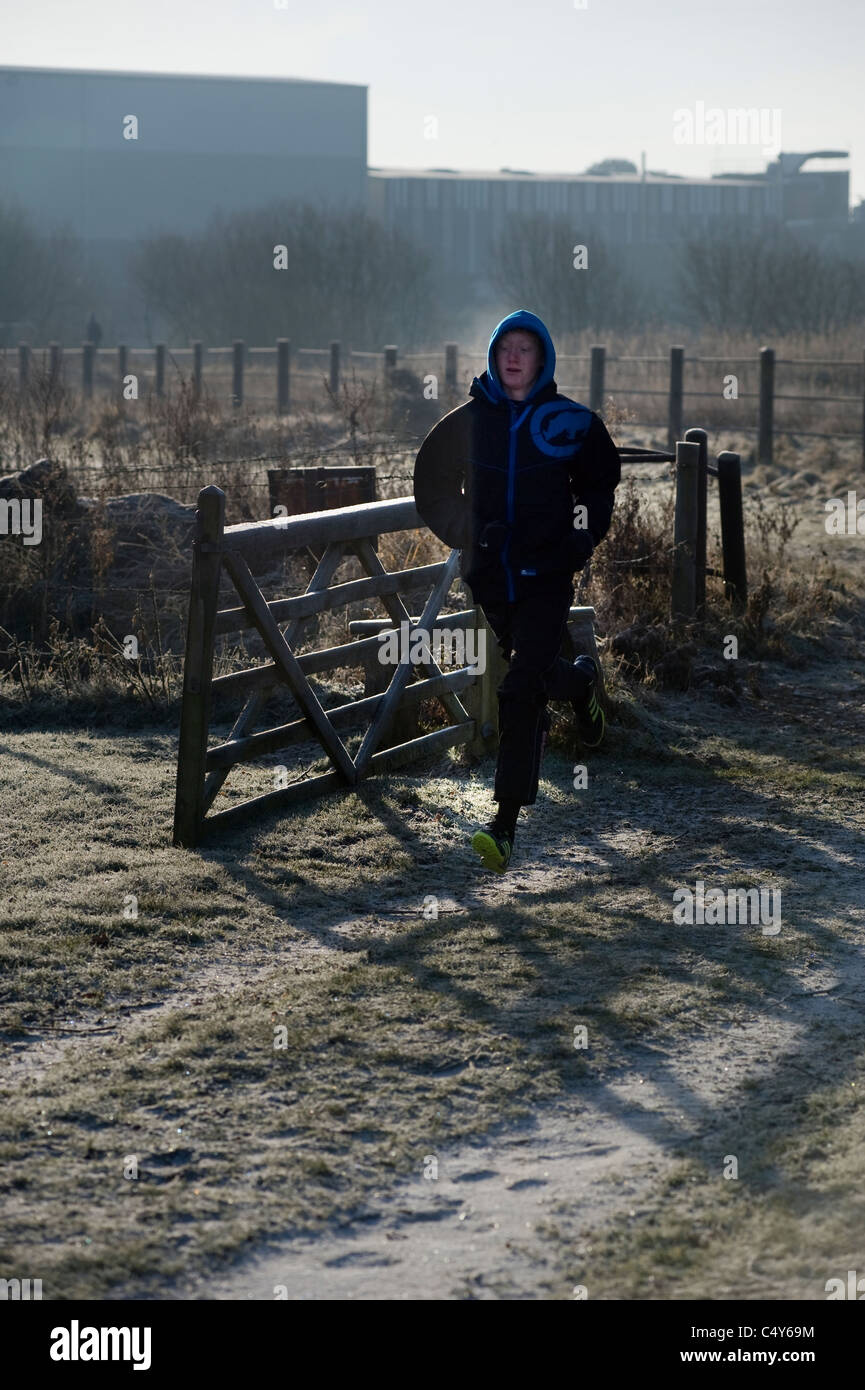 young man running through farm gate on frosty morning Stock Photo
