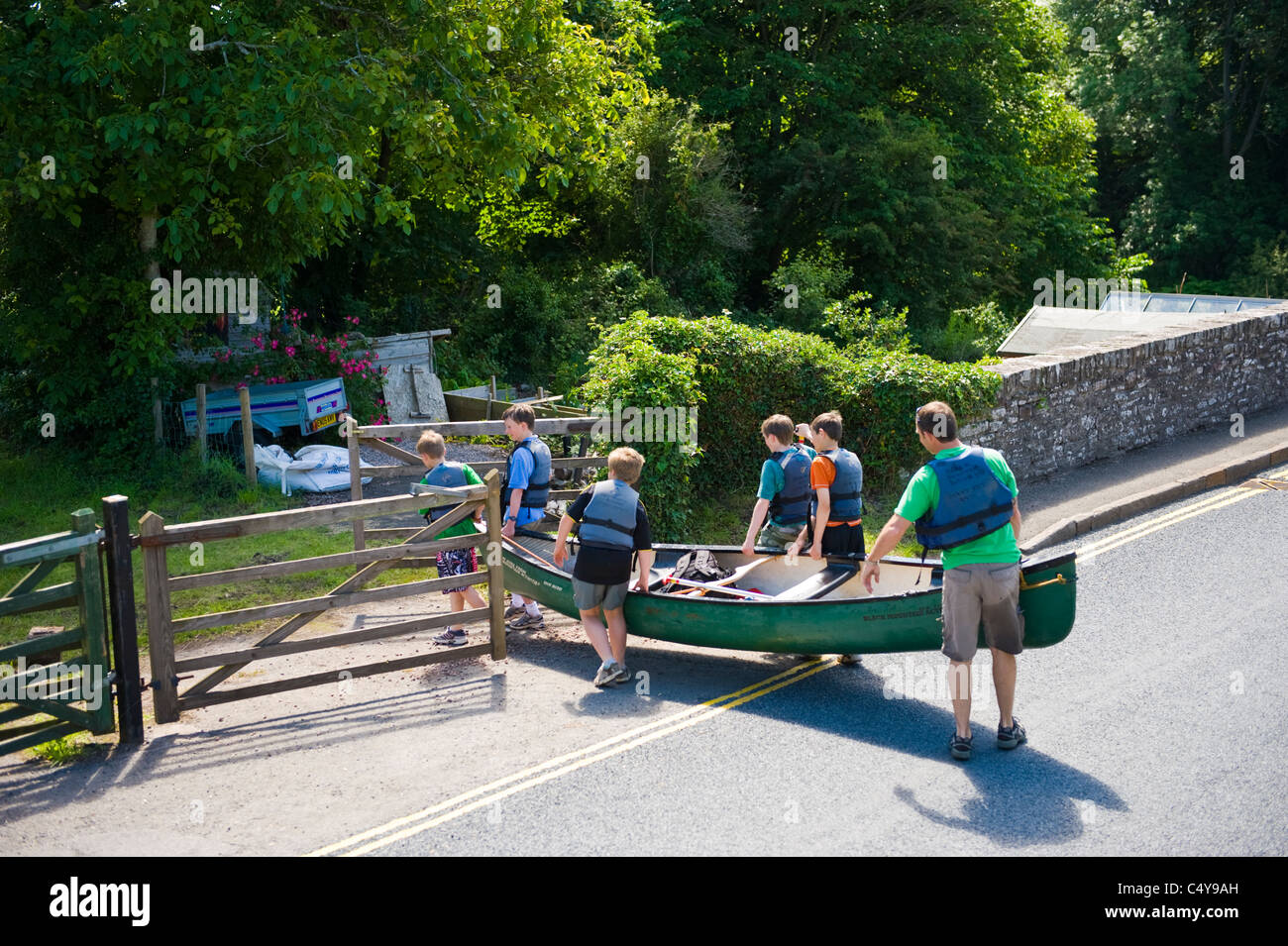 Canoeists carrying open canoe across road near Brecon Powys South Wales