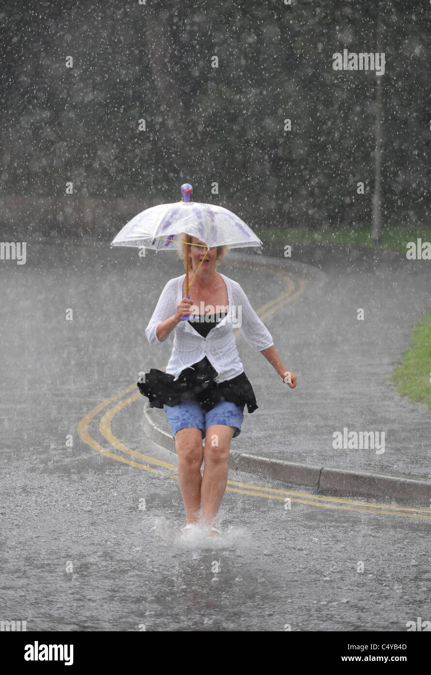 A woman makes a dash for cover under a brolly during torrential rain in Brighton today Stock Photo