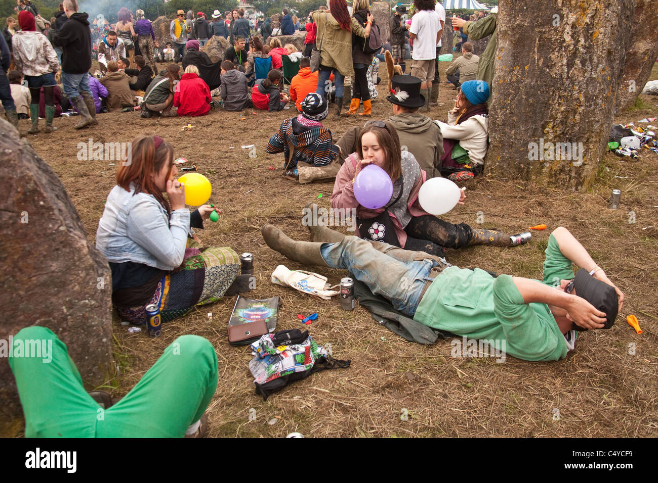 Taking balloons of nitrous oxide ( laughing gas ) to get high at the stone circle in Kings Meadow, Glastonbury Festival 2011 Stock Photo