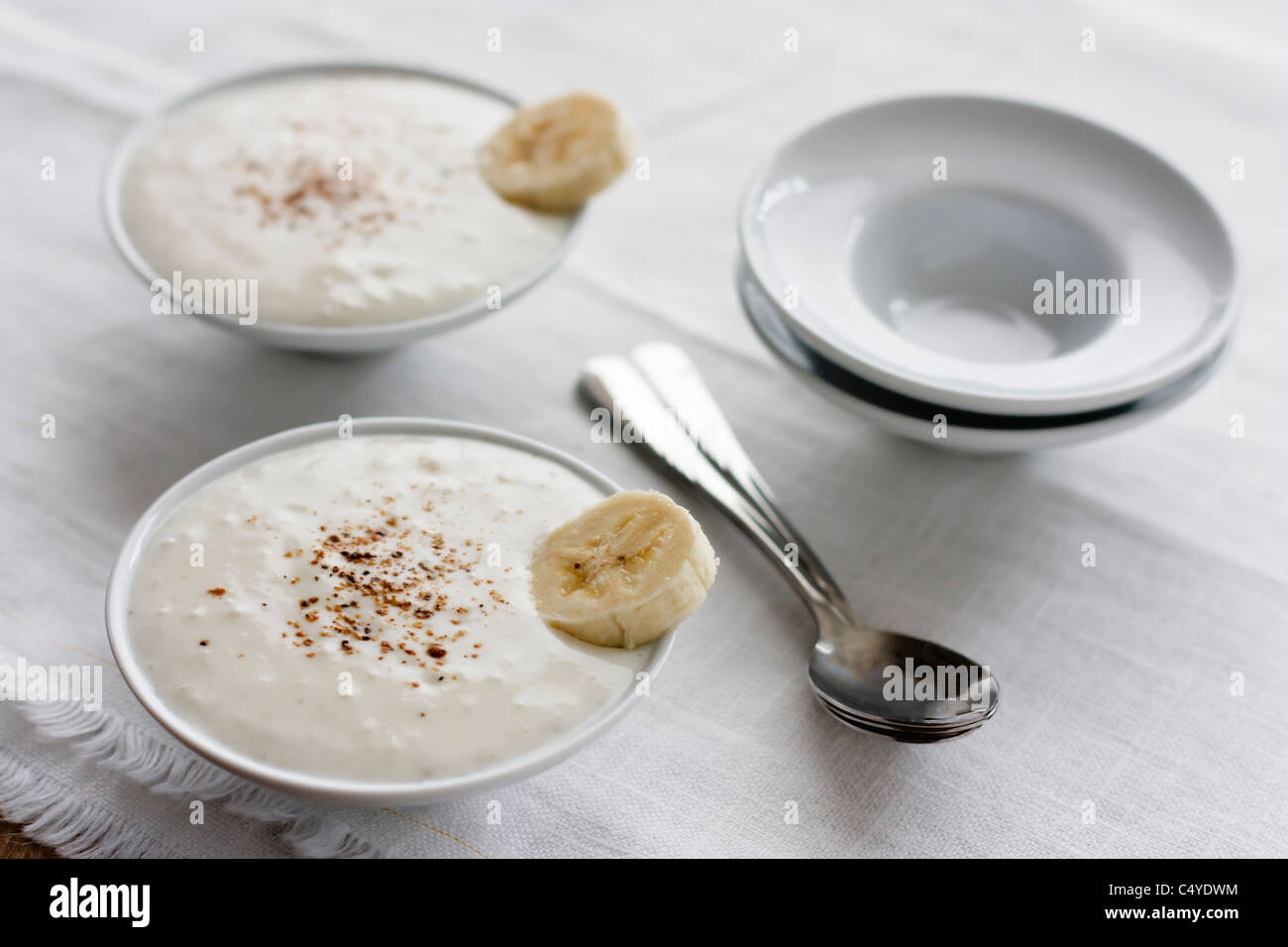 Bowls with Indian banana yoghurt flavored with garam masala served on a white table Stock Photo