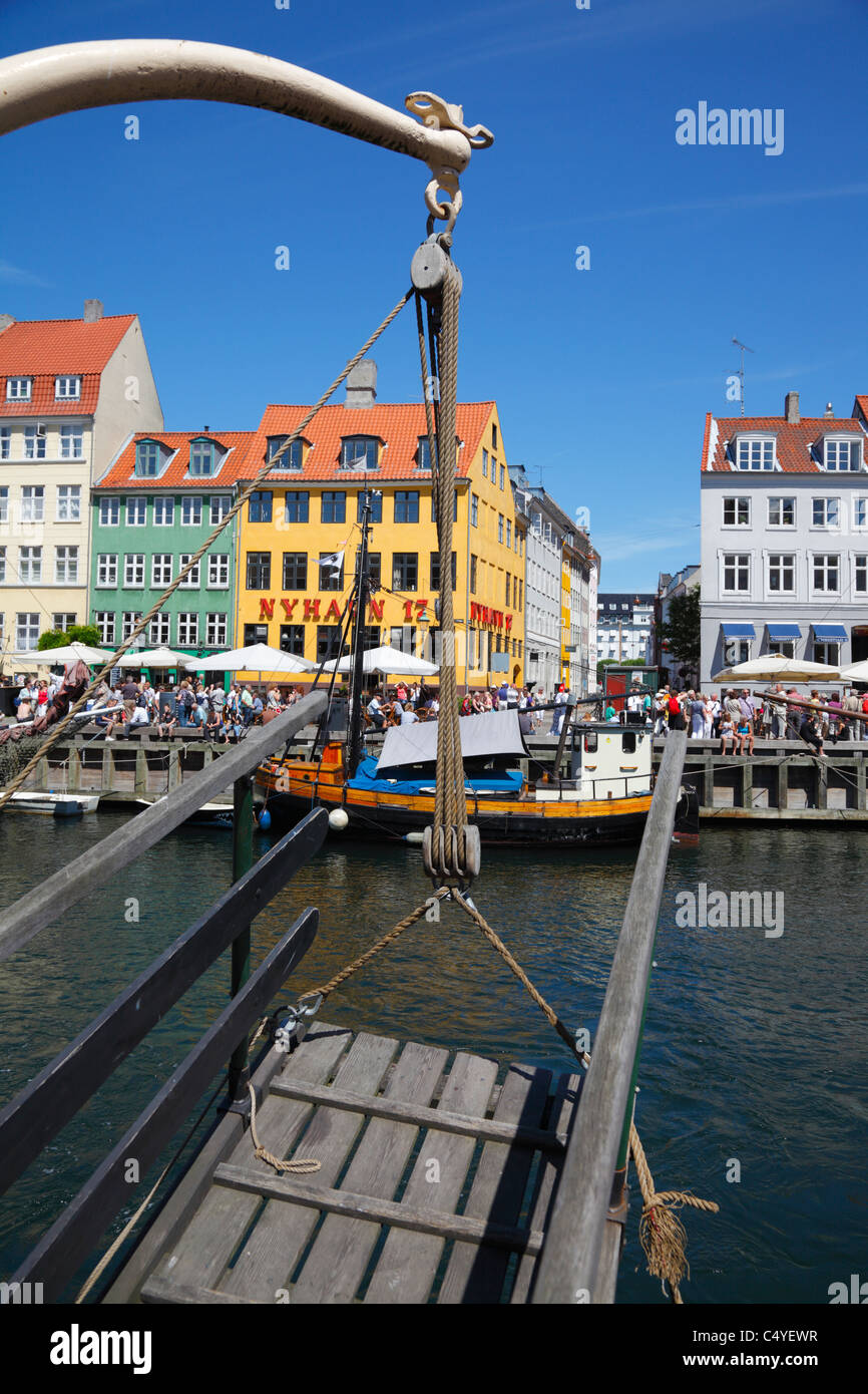 The Nyhavn canal and entertainment quarters in the port of Copenhagen seen through a wooden gangway hanging from a davit Stock Photo