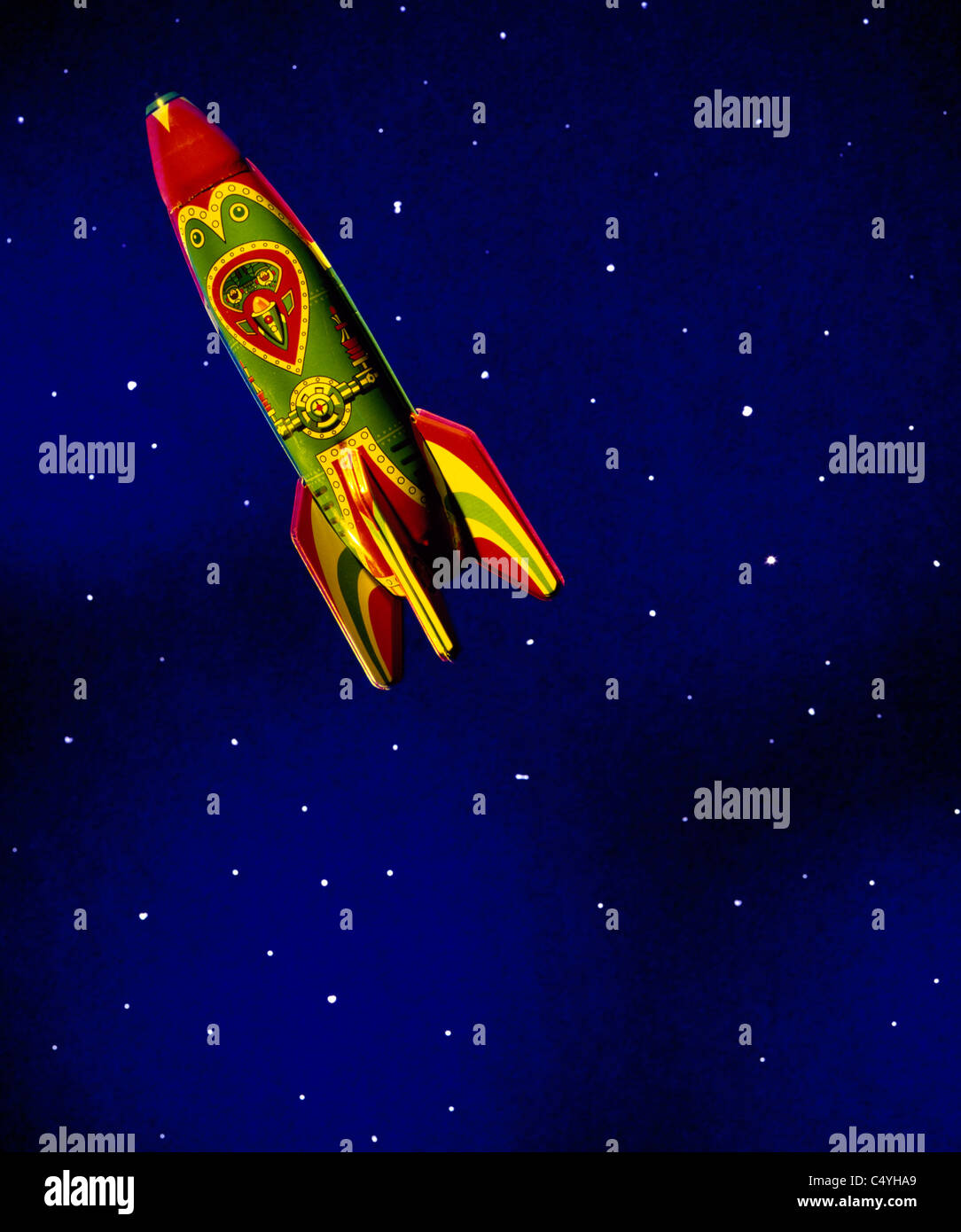 A children's toy rocket ship floating in dark blue space and stars Stock Photo