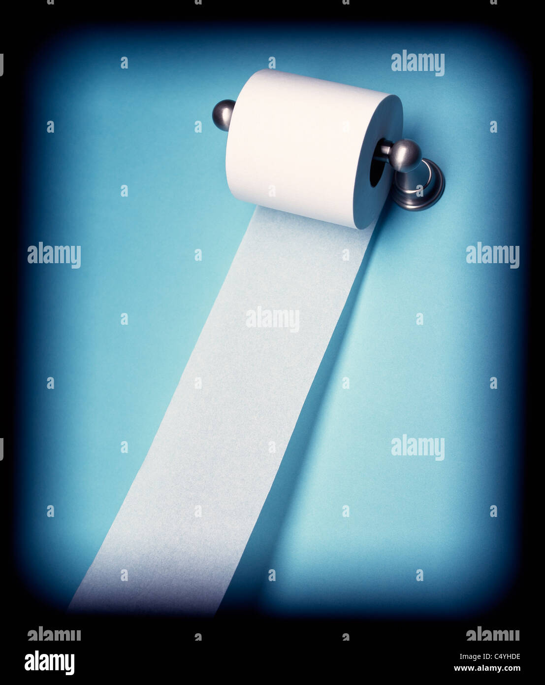 A toilet paper holder with paper rolling downwards Stock Photo