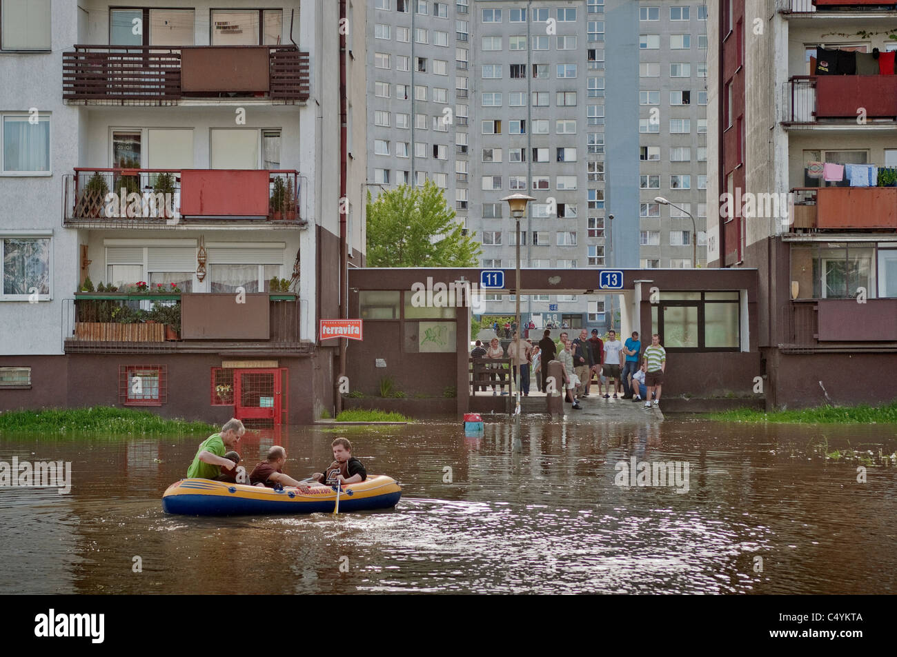 Men in pontoon paddling across flooded area near entrance to apartment building, 2010 flood at Kozanow area of Wrocław, Poland Stock Photo