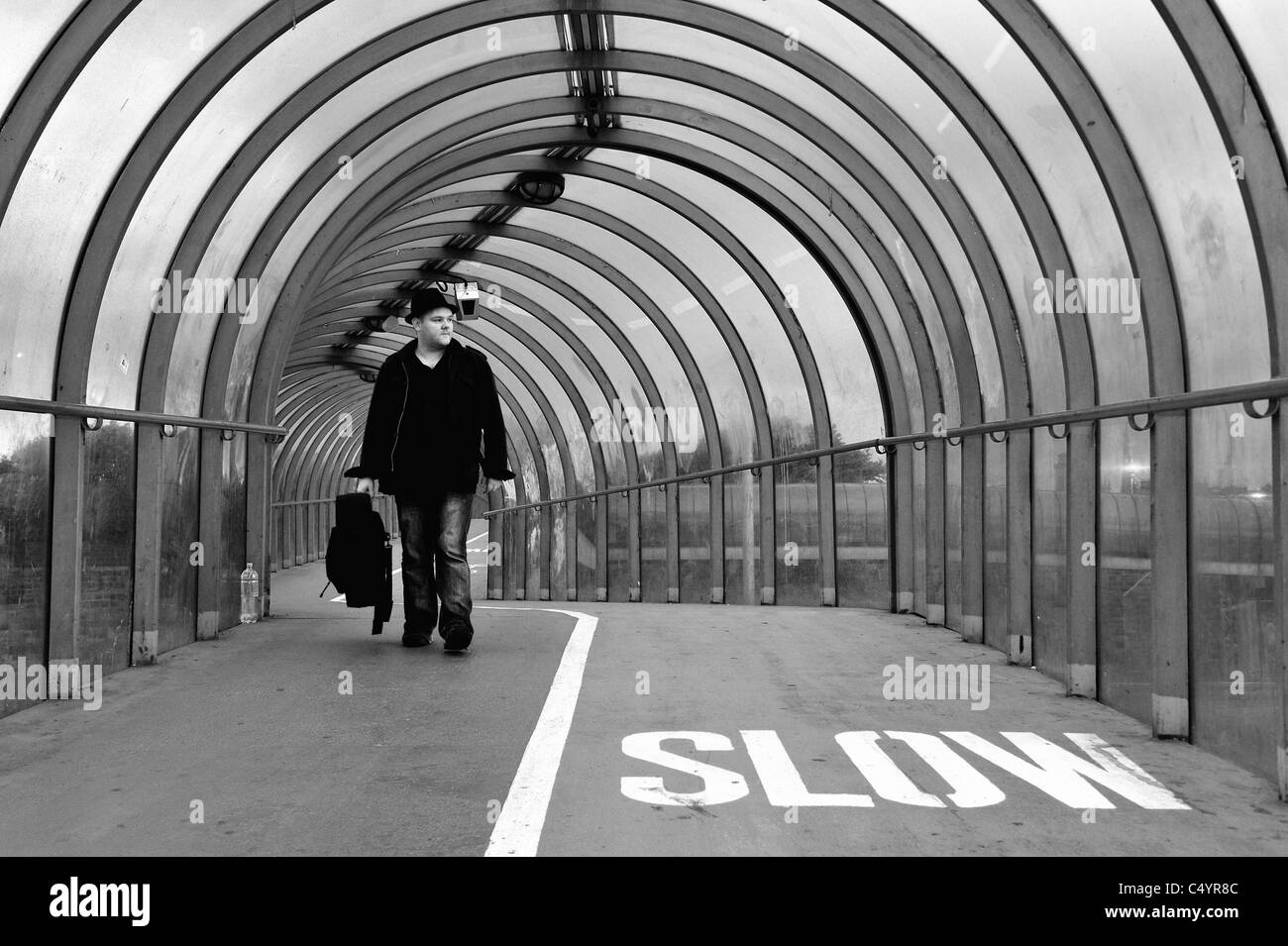 A man carrying a guitar case walks through the SECC tunnel in Glasgow Stock Photo