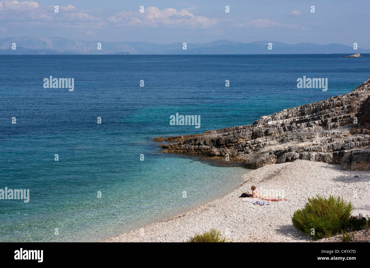 A young woman sunbathes on Kloni Gouli beach. Paxos, Greece. Stock Photo