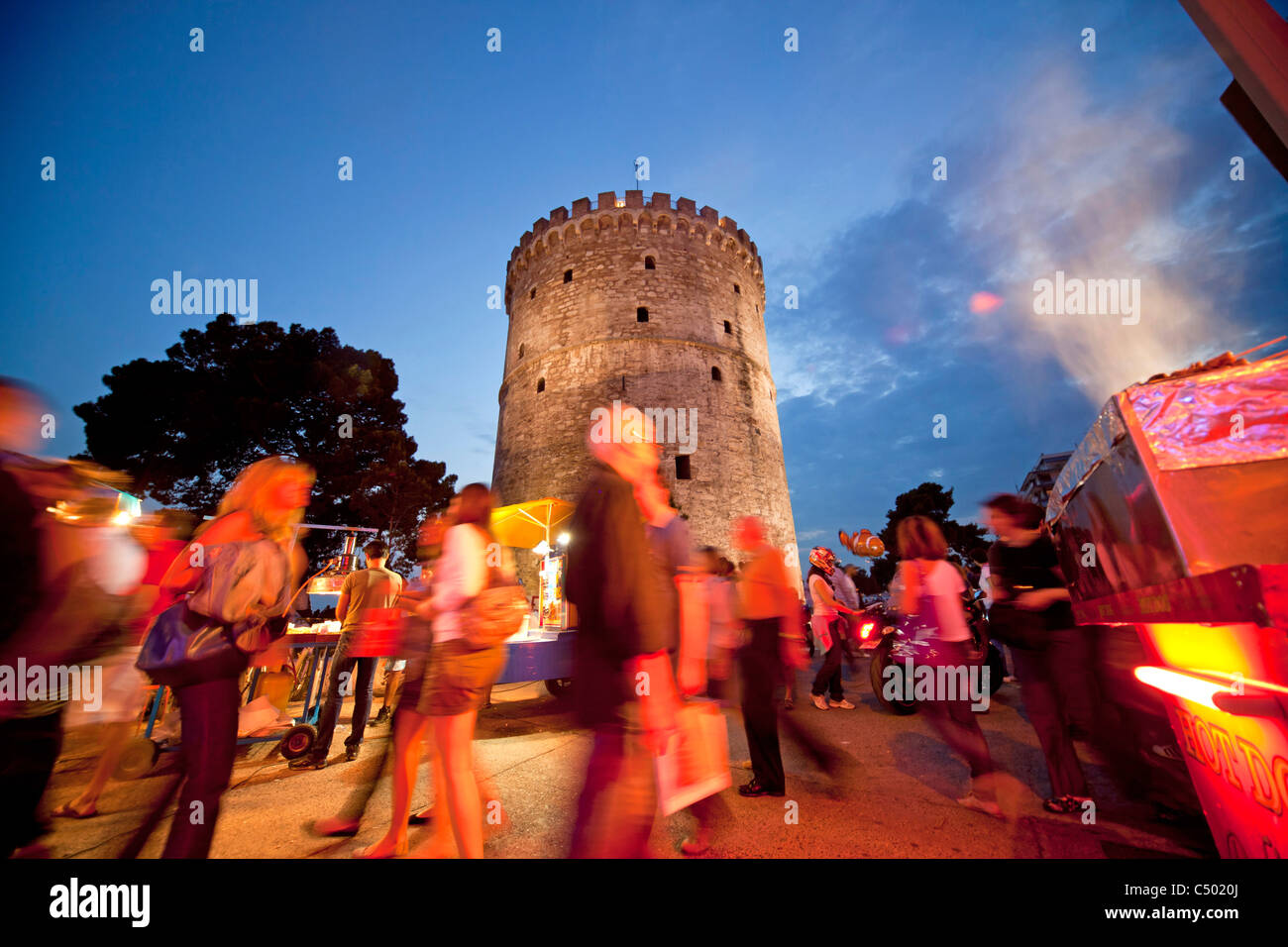 a busy evening at the illuminated white tower, symbol of the town of Thessaloniki, Macedonia, Greece Stock Photo