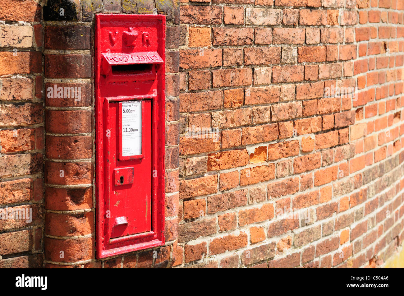 A Victorian Royal Mail postbox built into a brick wall in England. Stock Photo