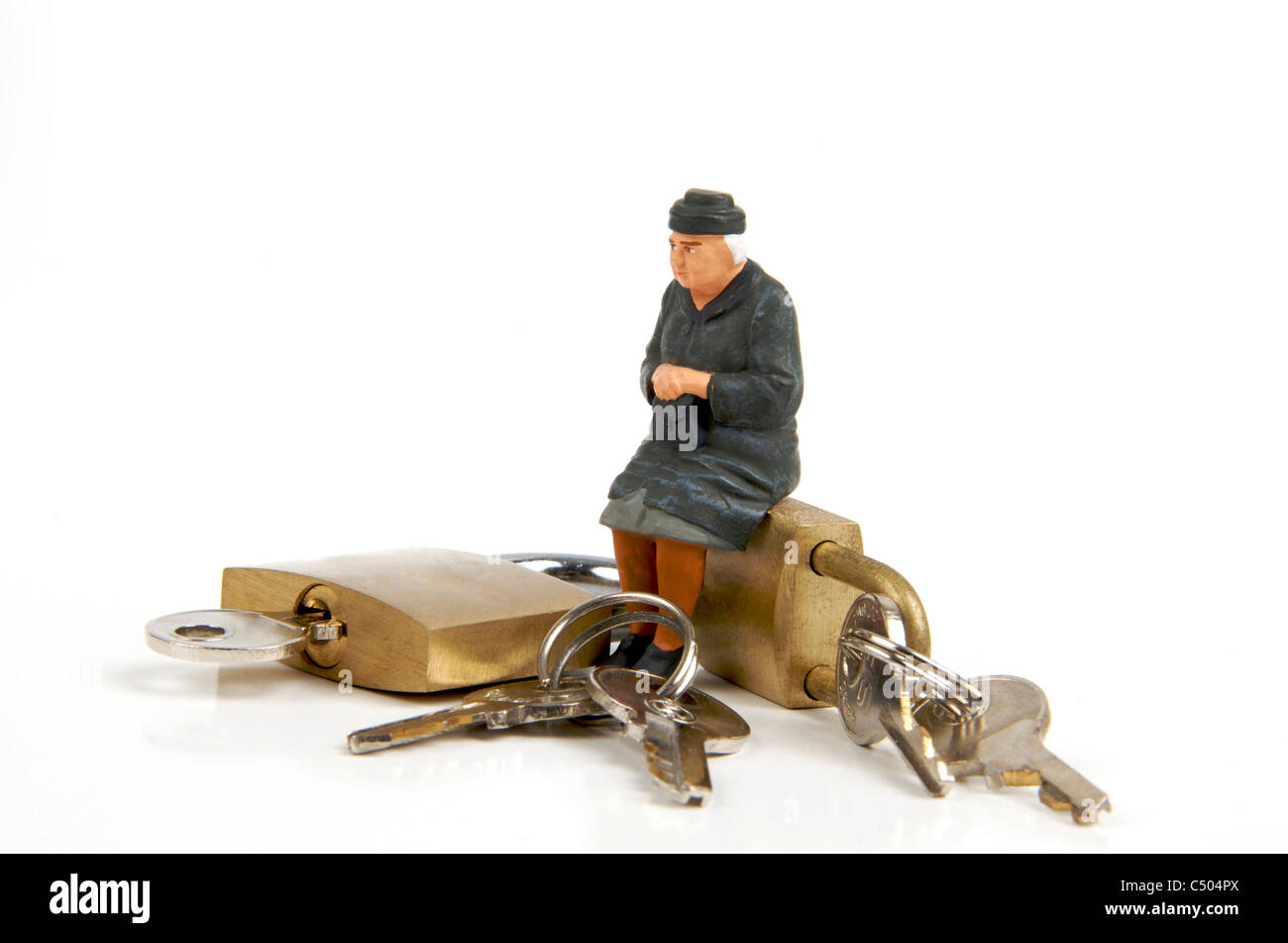 Miniature figurine of elderly lady sitting on padlocks - retirement / security / housing concept Stock Photo