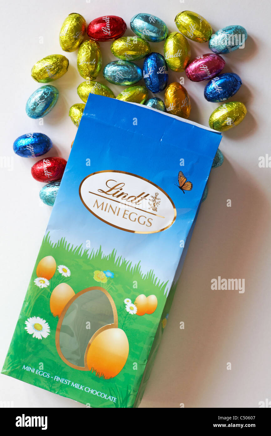 Packet of Lindt mini eggs finest chocolates with foil wrapped eggs spilled on white background - ready for Easter Stock Photo