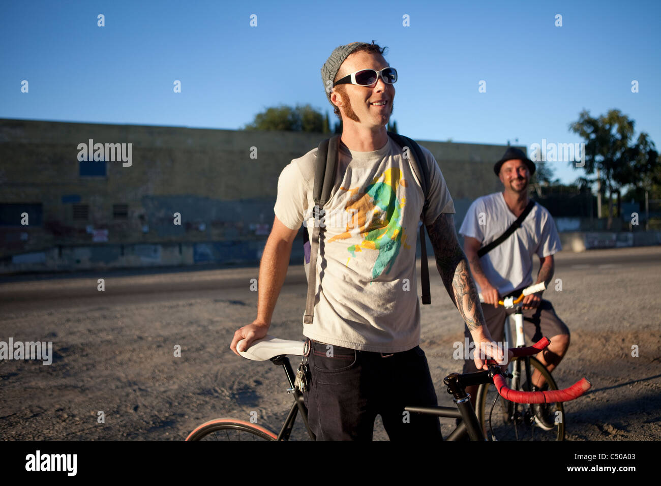Caucasian bicycle messengers stopping on city street Stock Photo