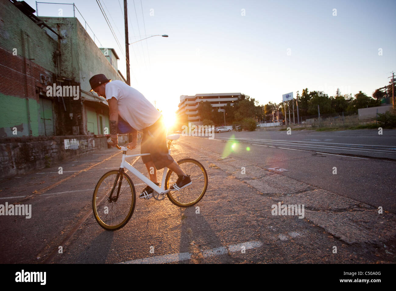 Man doing stunts on bicycle on city street Stock Photo