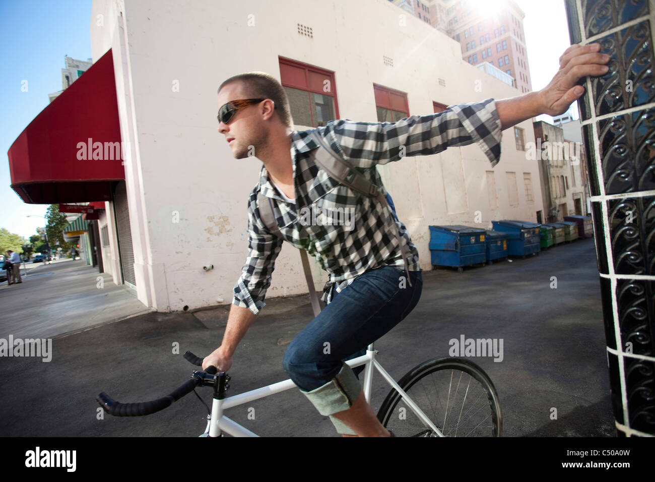 Bicycle messenger stopping on city street Stock Photo