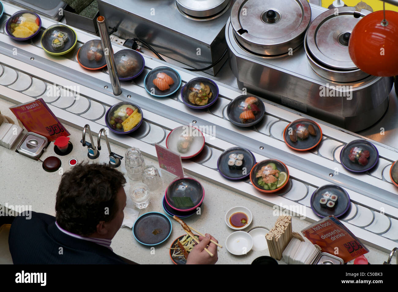 man eating sushi train Stock Photo