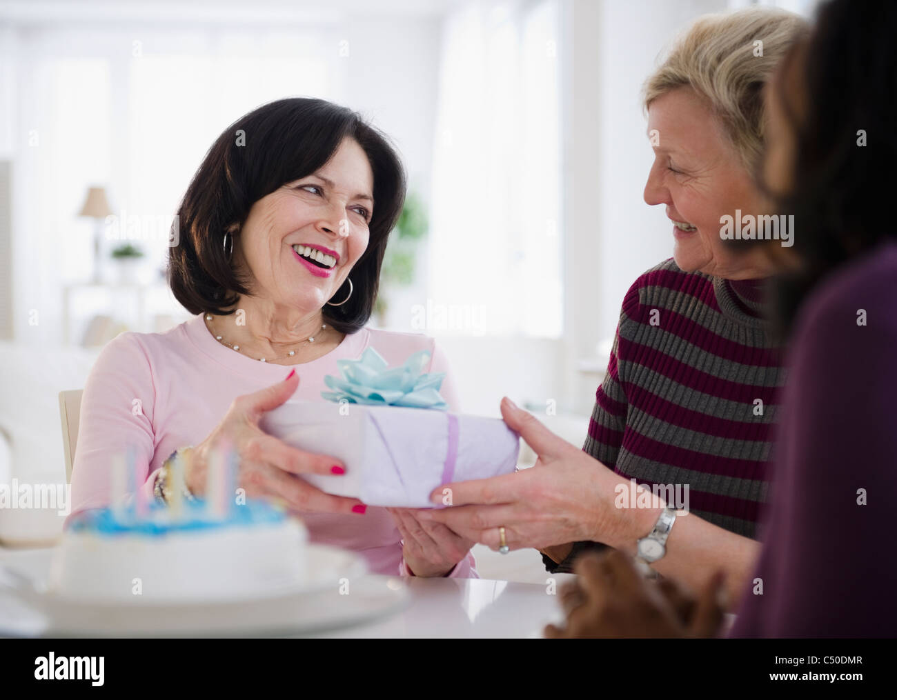 Women surprising friend with birthday cake and gift Stock Photo