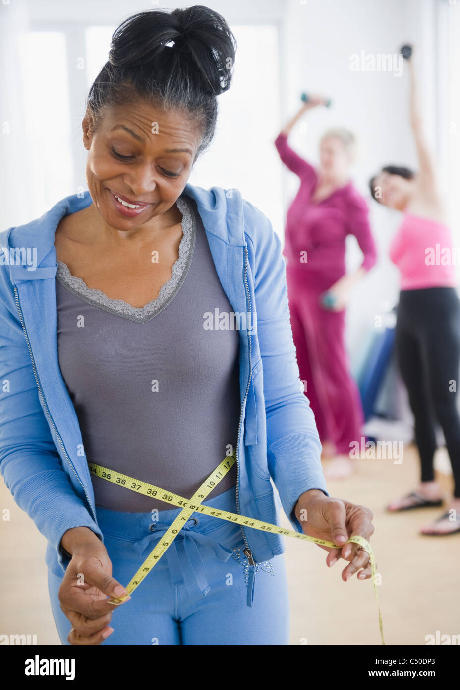 https://c8.alamy.com/comp/C50DP3/mixed-race-woman-measuring-her-waist-C50DP3.jpg