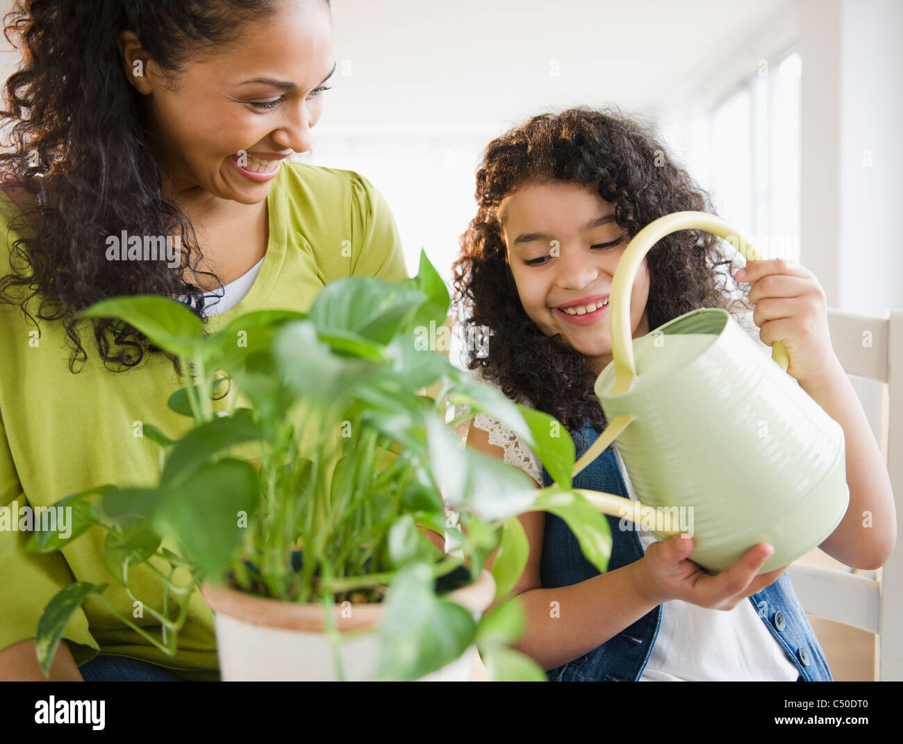Mother and daughter watering plant together Stock Photo - Alamy