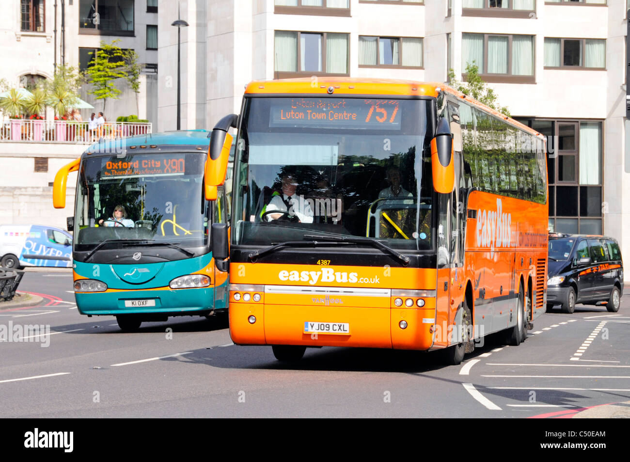 Drivers of two public transport coach bus services enroute to Luton & Oxford with one operated by EasyBus driving along Park Lane London England UK Stock Photo