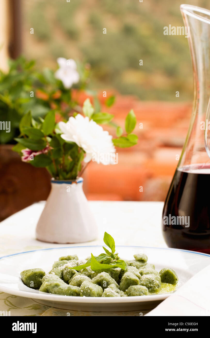 Spinach gnocchi and carafe of red wine Stock Photo