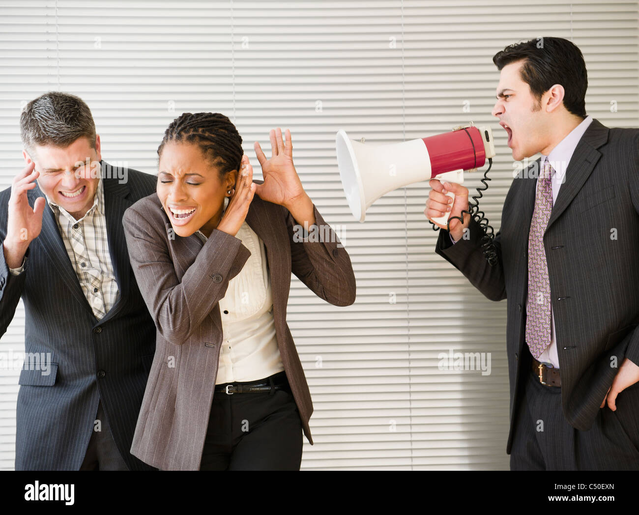 Businessman shouting through bullhorn at co-workers Stock Photo