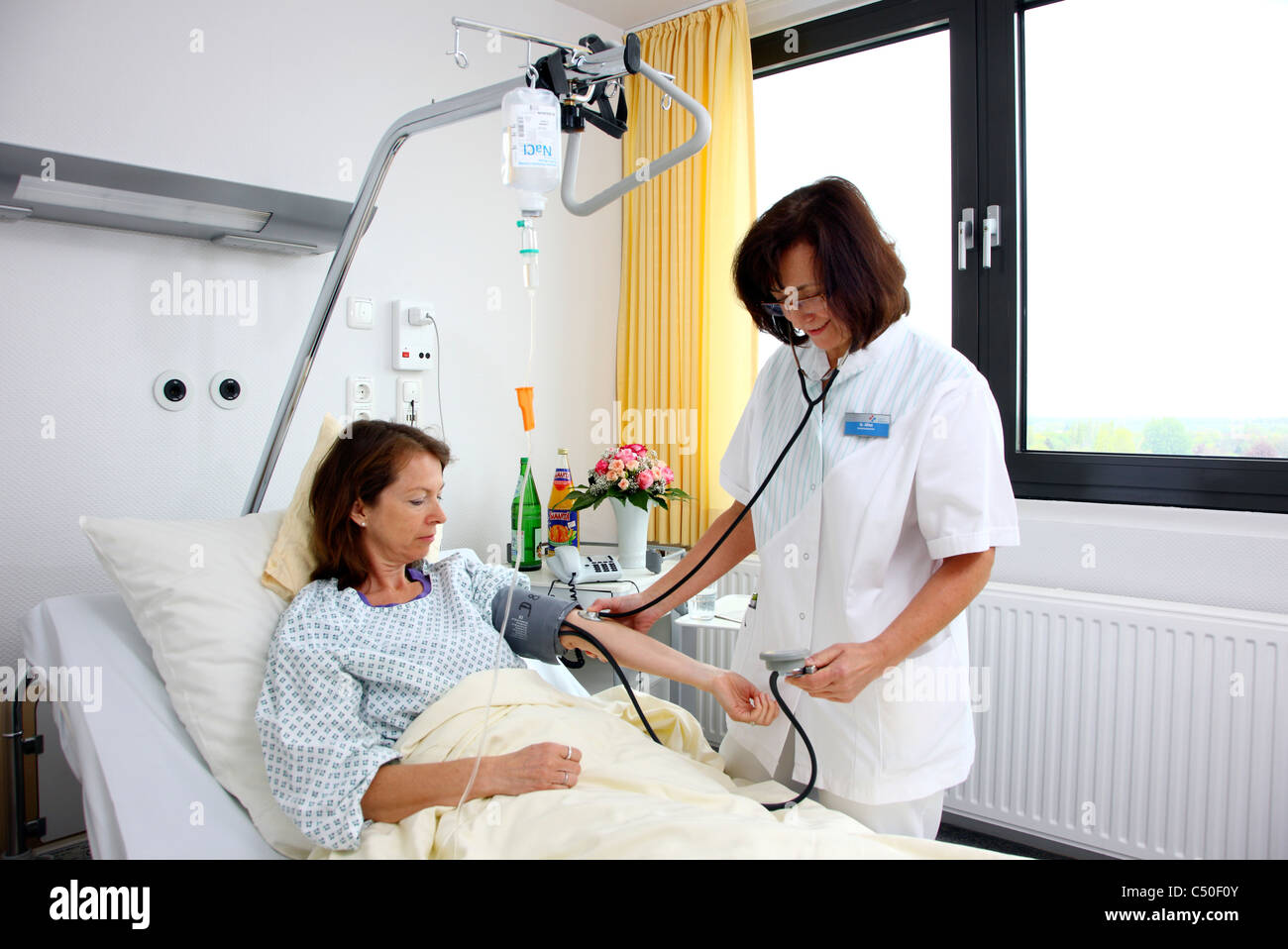 Hospital. Nurse is checking blood pressure of a female patient. Stock Photo