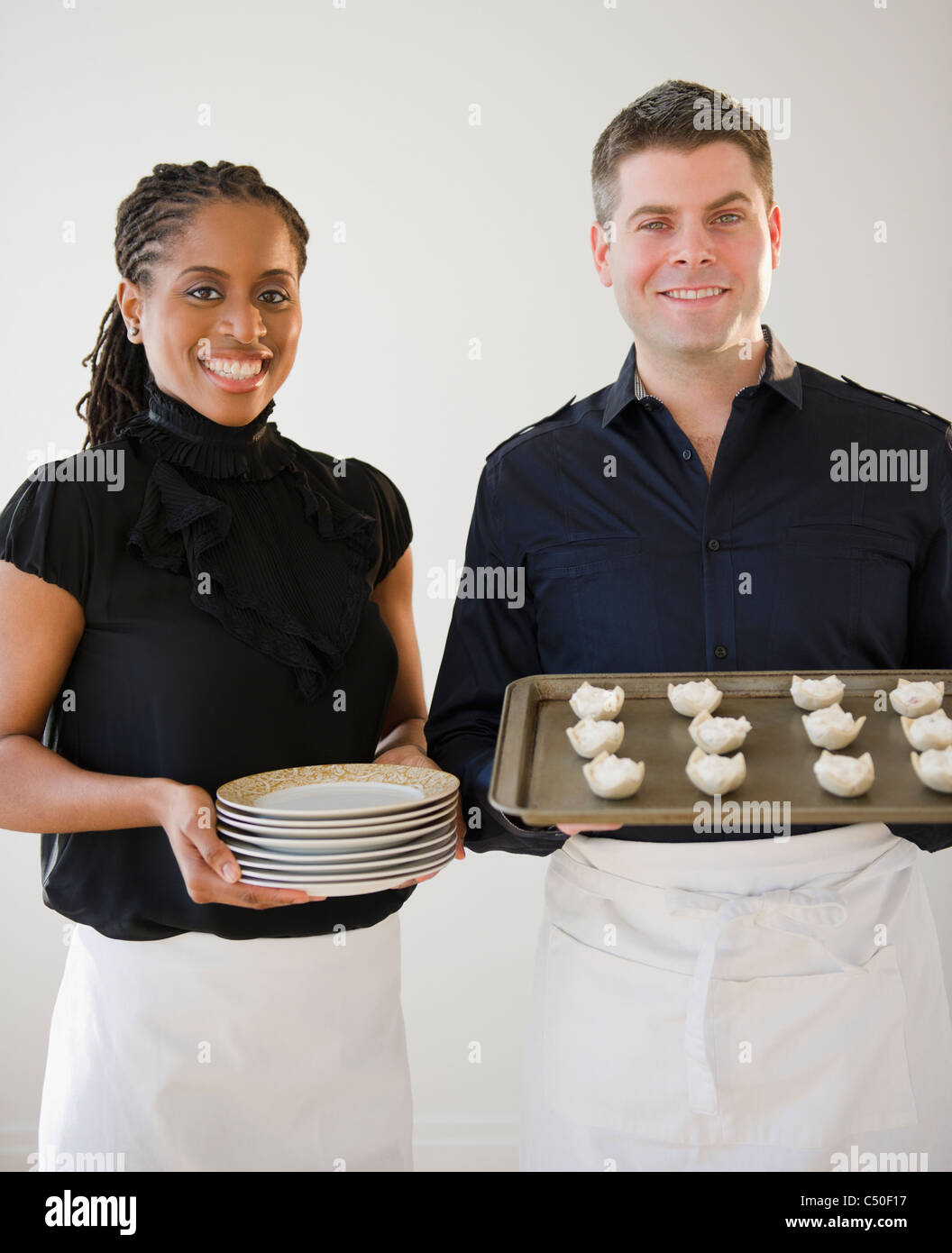 Caterers holding plates and tray of food Stock Photo