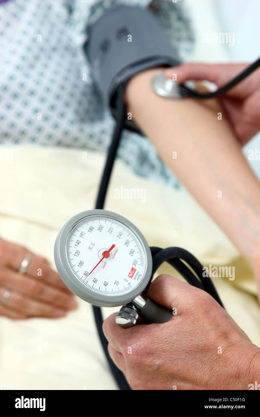 Hospital. Nurse is checking blood pressure of a female patient. Stock Photo