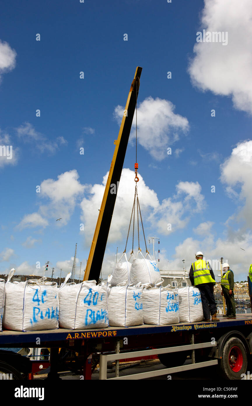 Bags of ballast being hoisted off the back of a lorry by a crane Stock