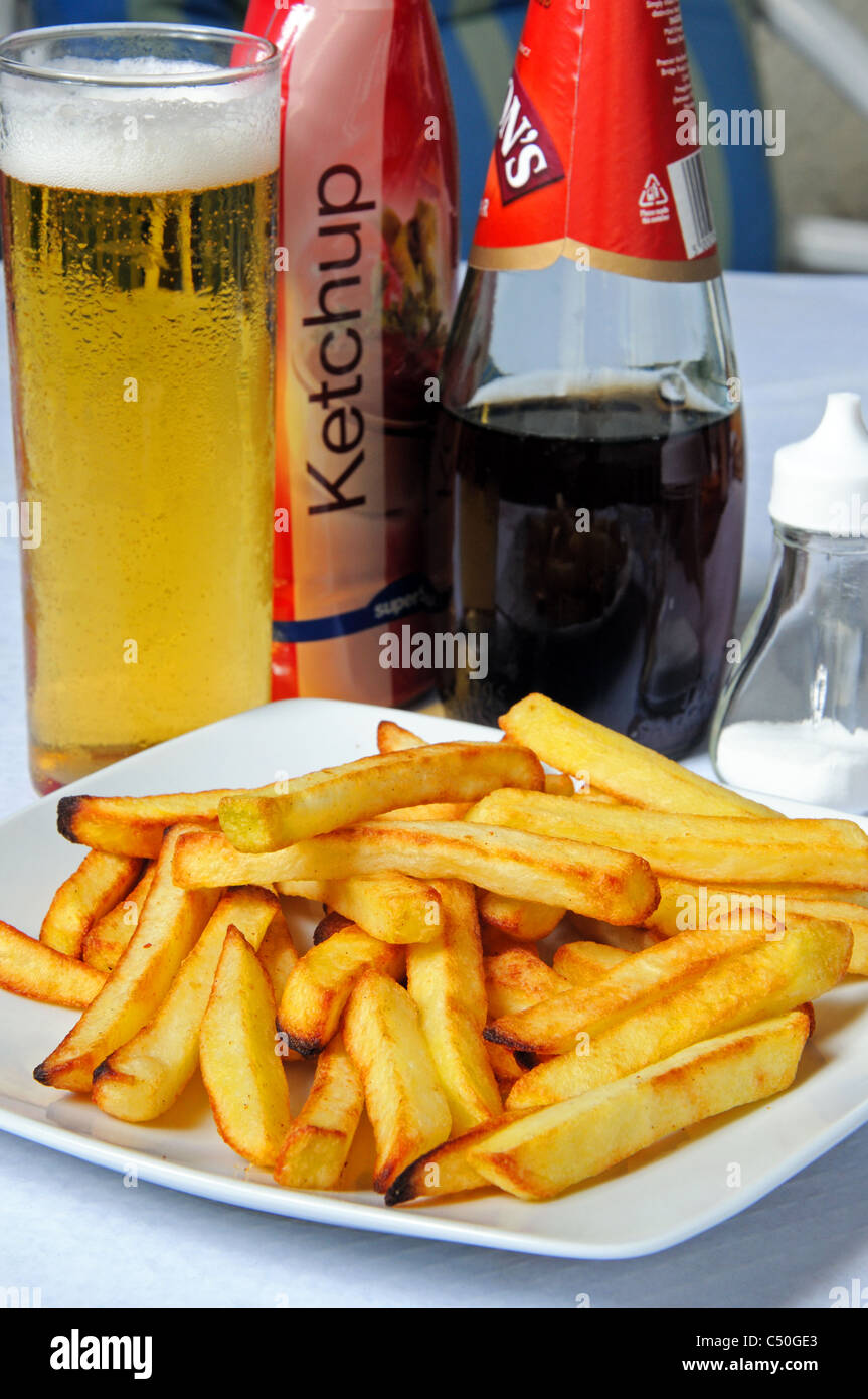 Chips (French fries) with salt, vinegar and ketchup bottles to the rear