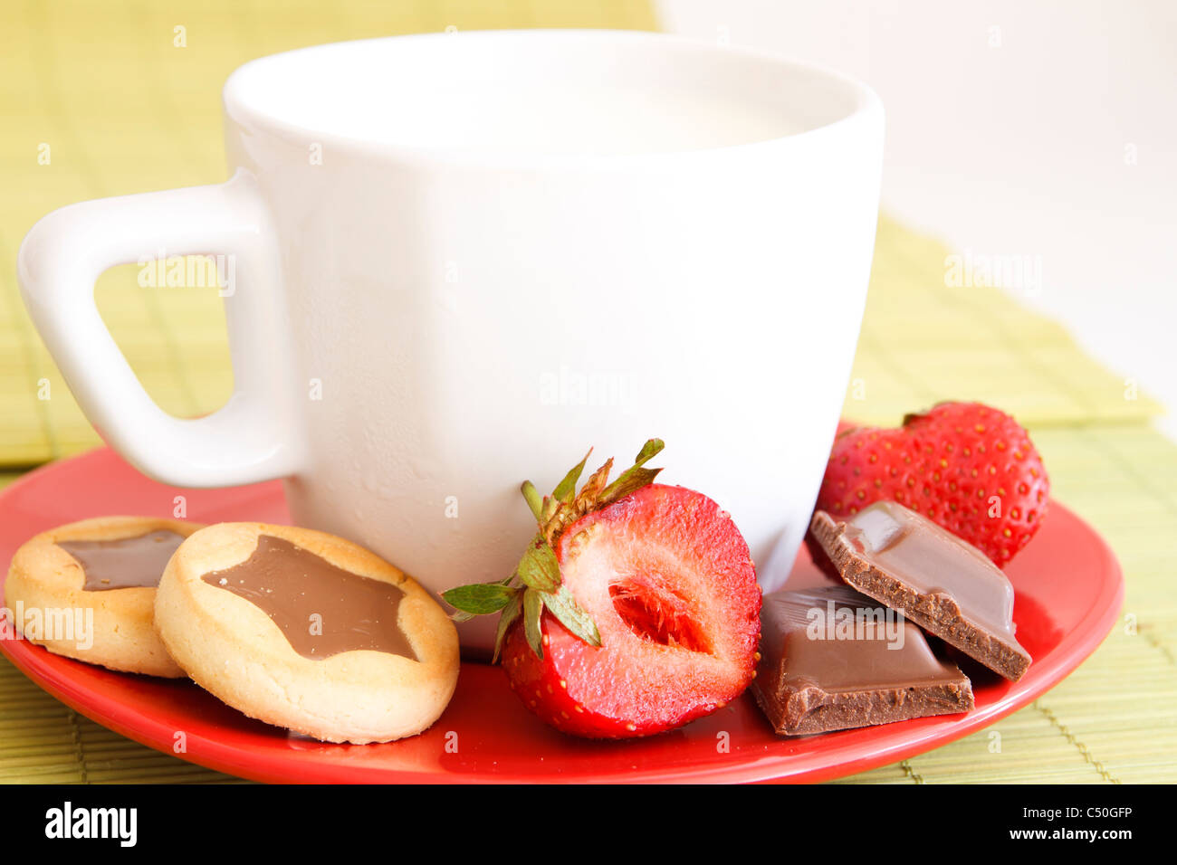 withe cup of milk and cakes and chocolate and strawberries Stock Photo