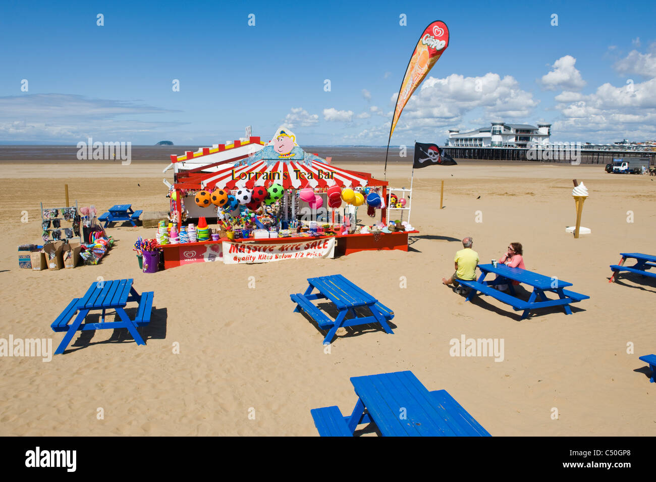 Tea Bar with novelty goods and blue benches on the sand beach at Weston Super Mare Somerset England UK Stock Photo