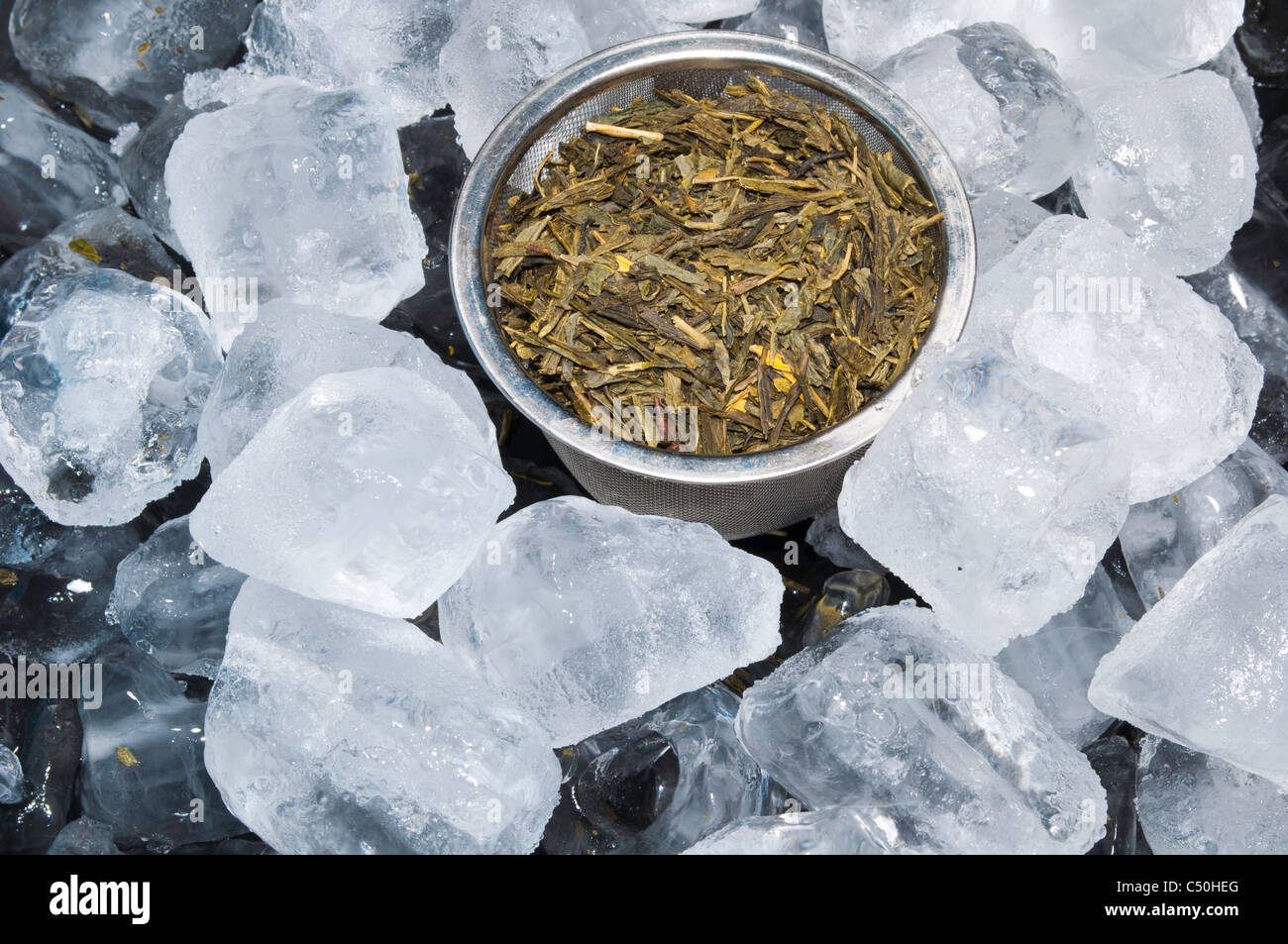 A Tea Infuser Basket with Green Tea Sitting on top of a Bed of Ice Cubes Stock Photo