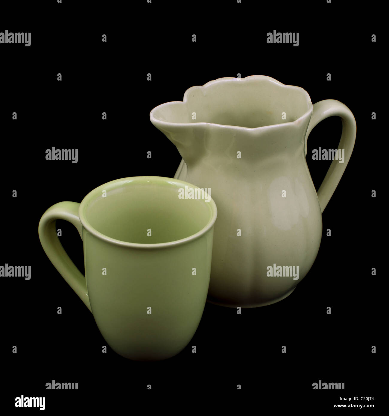 Old green ceramic pitcher and cup isolated on black background Stock Photo