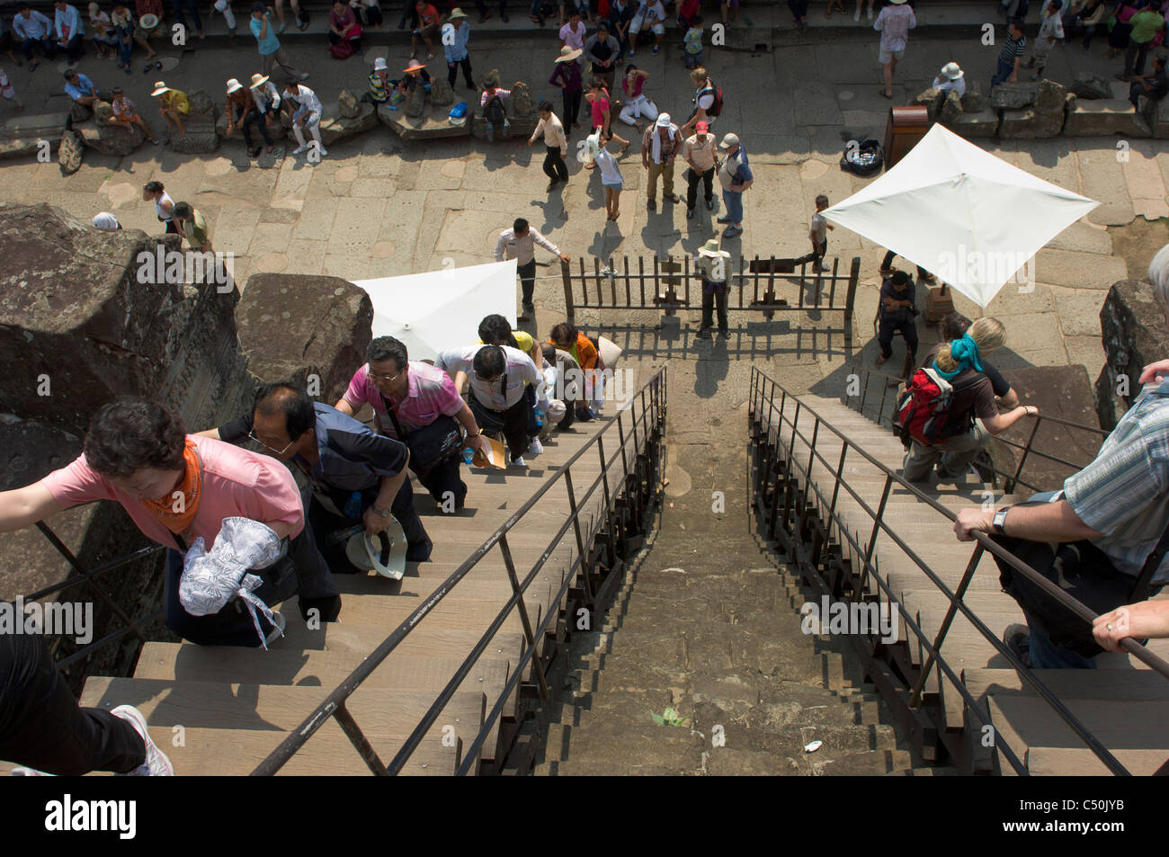 Tourists climbing up the steep steps leading to the third level of Angkor Wat, Angkor, Siem Reap, Cambodia Stock Photo