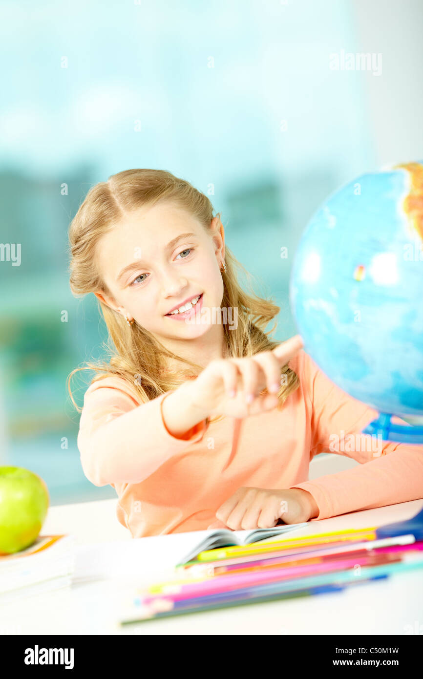 Portrait of cute schoolgirl pointing at globe at workplace Stock Photo ...