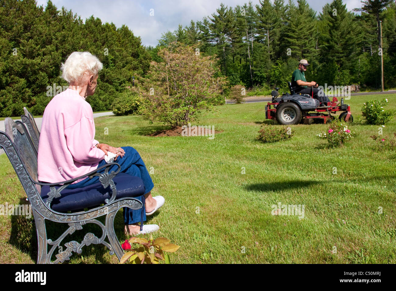 Lawn care service mowing elderly woman s lawn while she watches Stock Photo Alamy