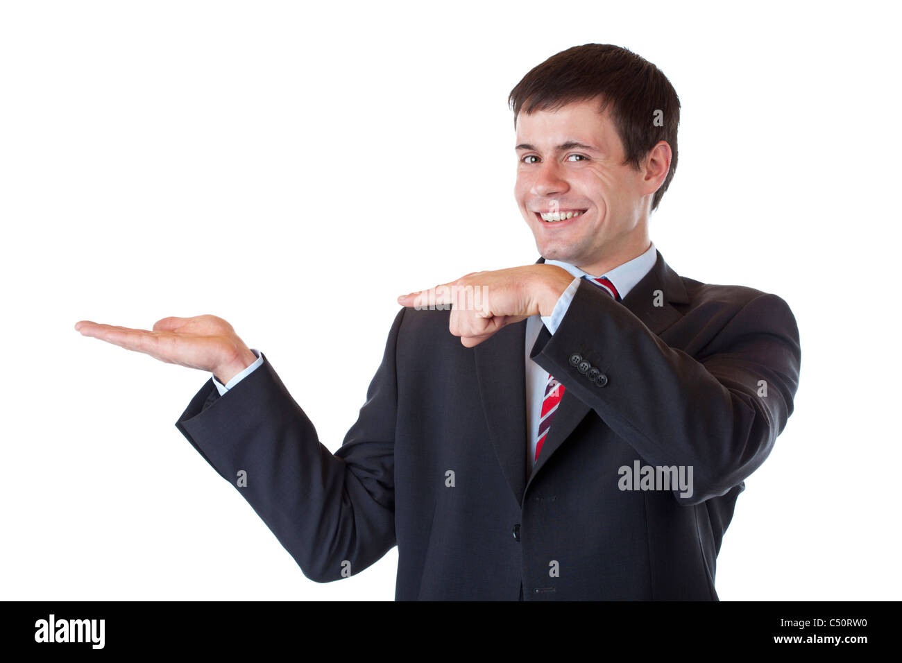 Young businessman points to ad text in his palm and smiles. Isolated on white background. Stock Photo