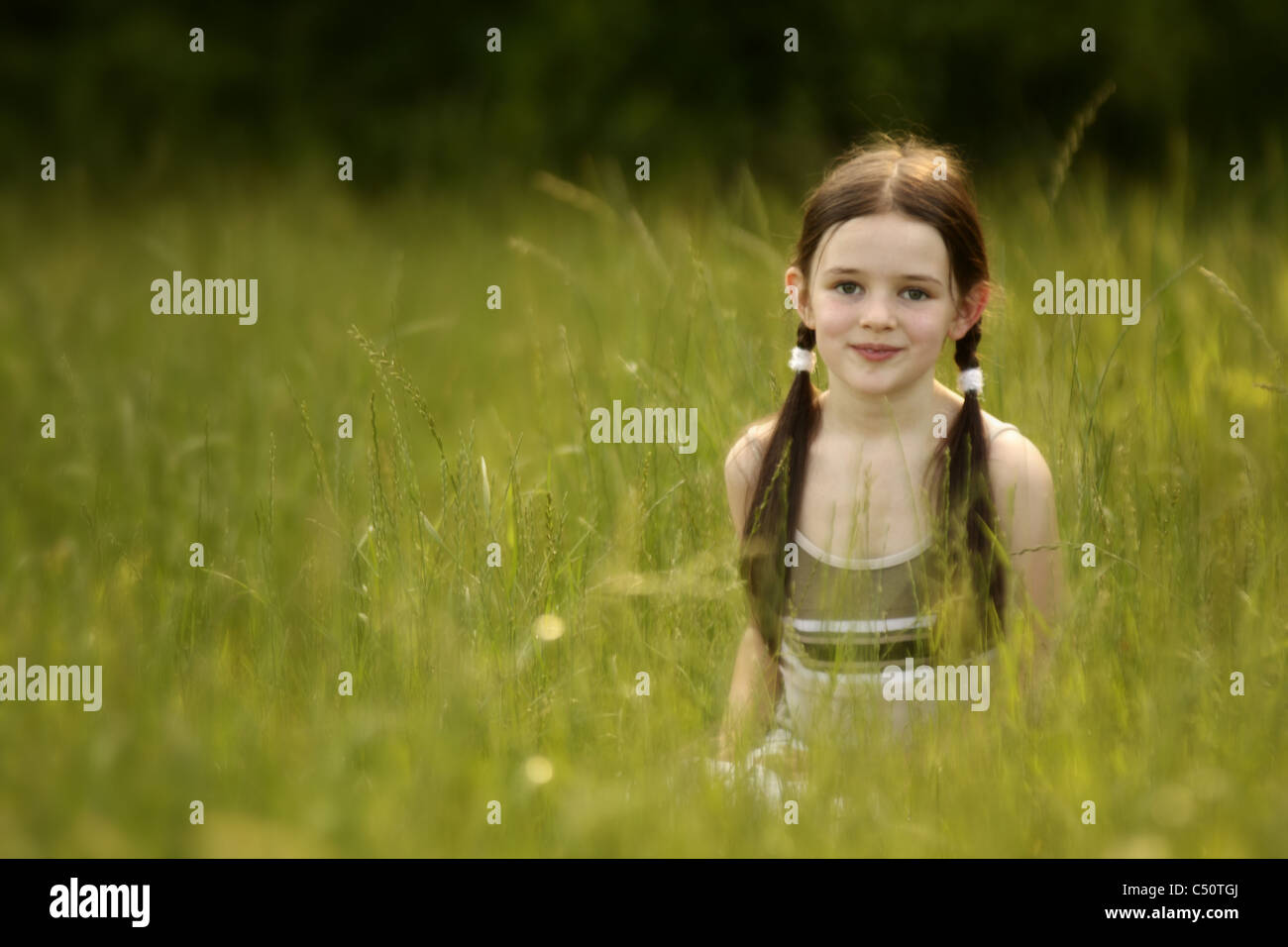 Smiling little Girl in a green field of tall grass Stock Photo - Alamy
