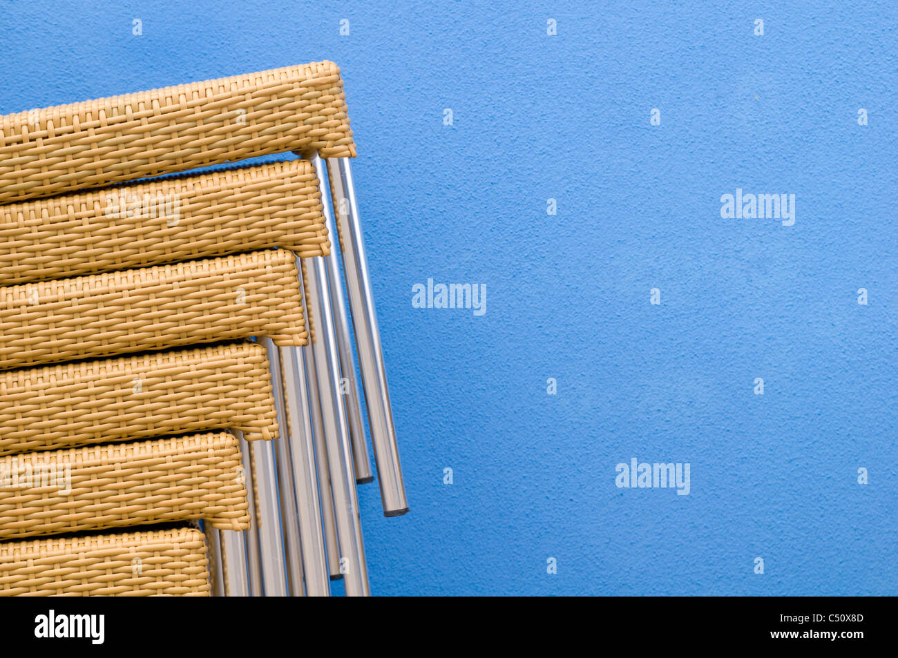Chairs stacked against the exterior blue wall of a restaurant in the