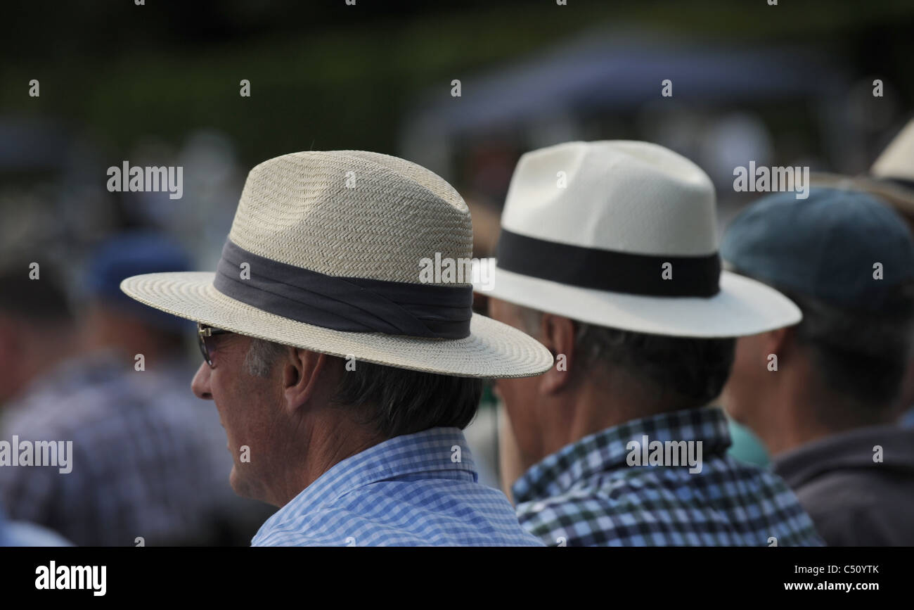 Men wearing panama hats enjoying a drink while watching a cricket