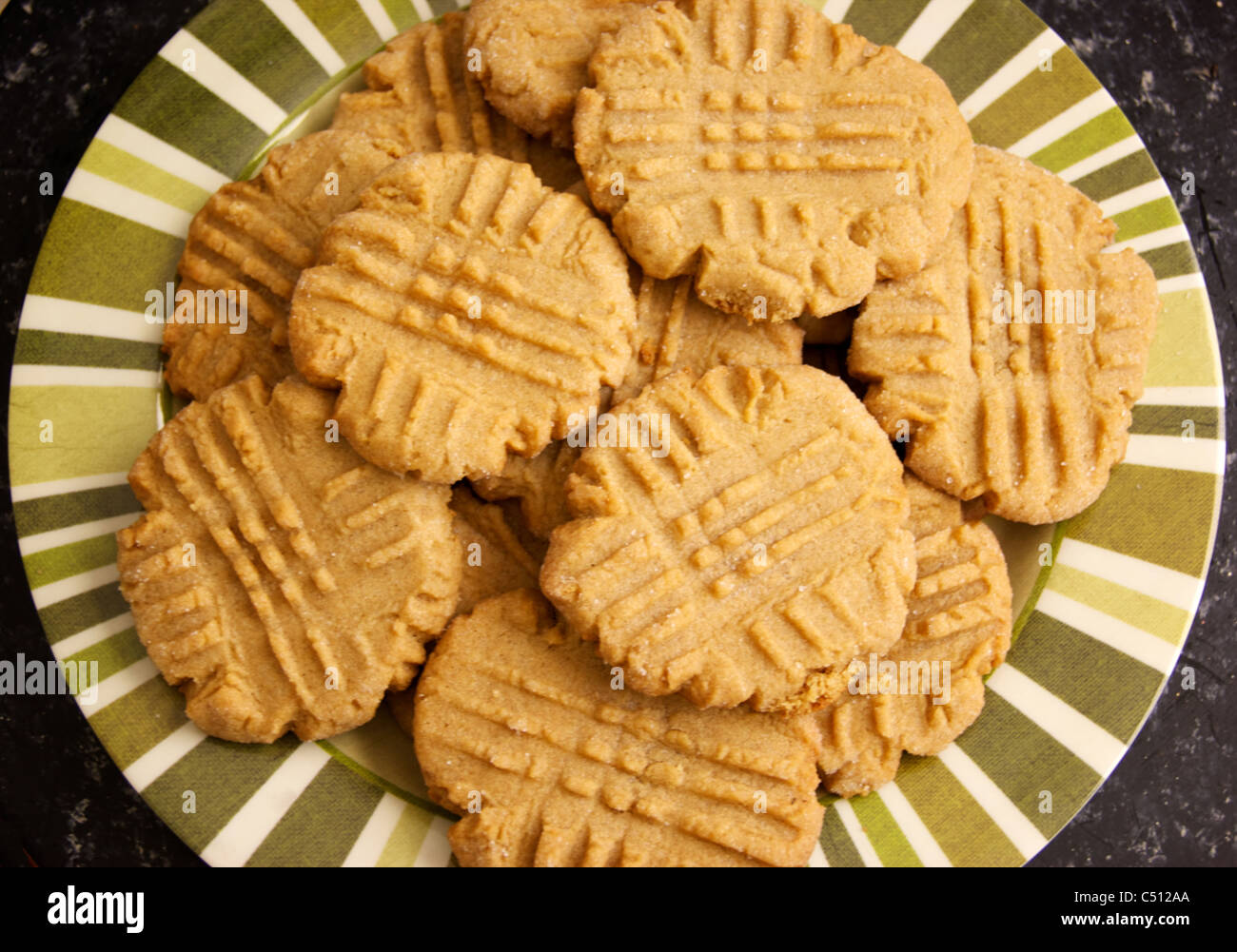 A striped plate holds a batch of fresh homemade peanut butter cookies