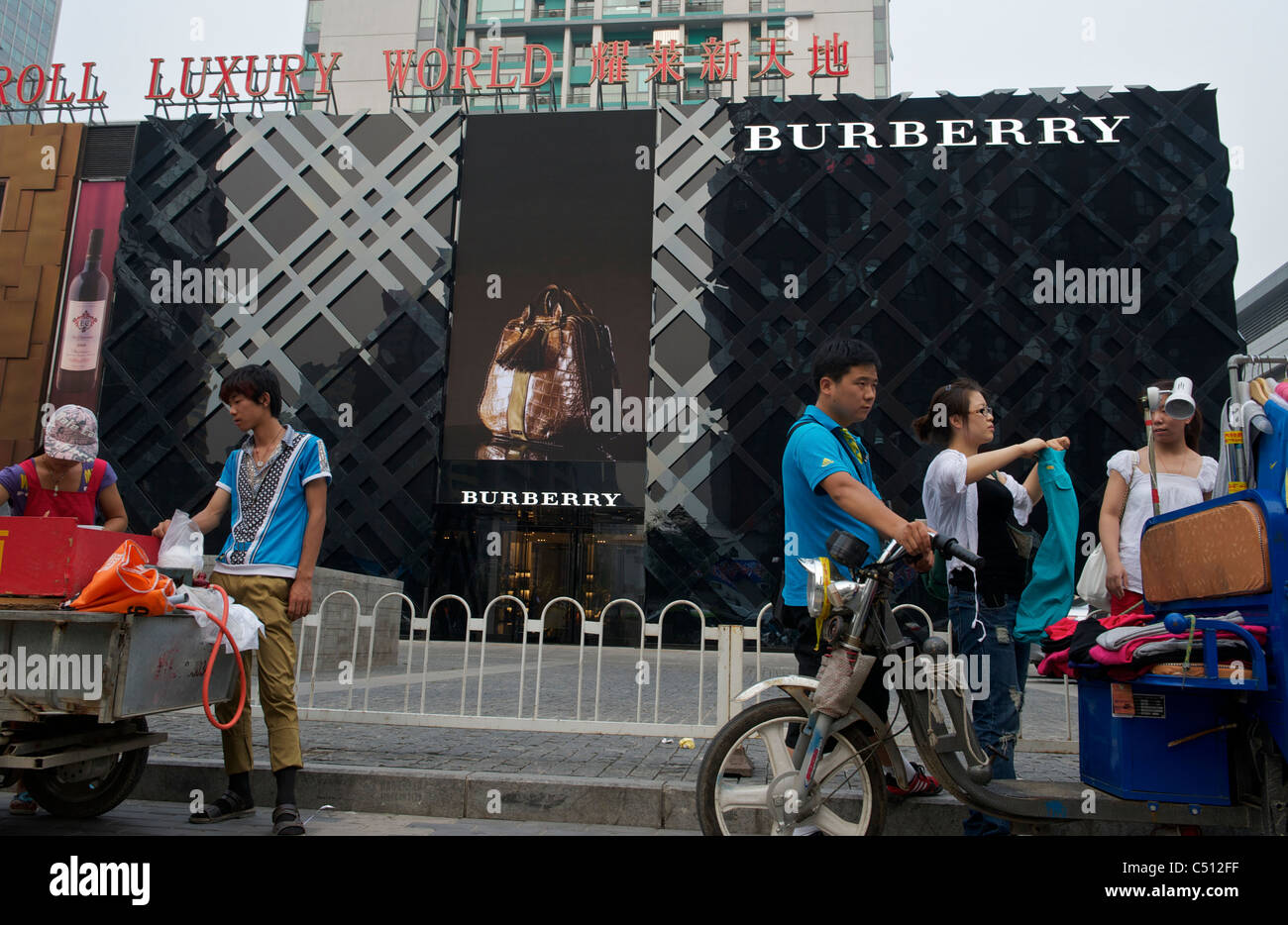 Chinese vendors sell cheap clothes in front of a Burberry Group Plc store in Beijing, China. 30-Jun-2011 Stock Photo